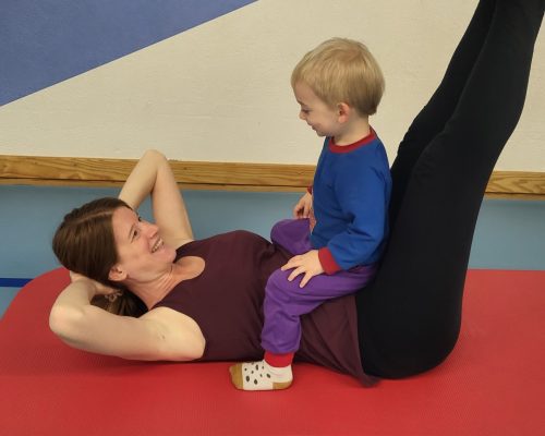 Mama macht Fitnessübungen mit Baby im Arm während eines Mamifitness-Kurses in Urdorf.