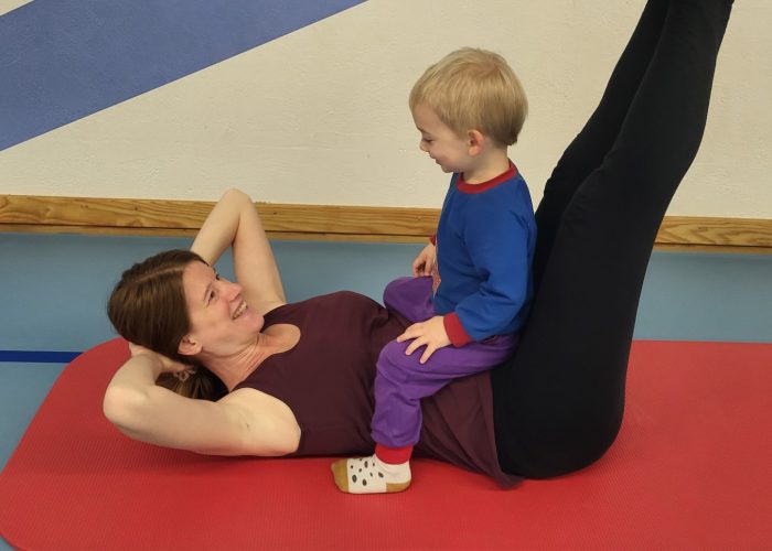 Mama macht Fitnessübungen mit Baby im Arm während eines Mamifitness-Kurses in Urdorf.