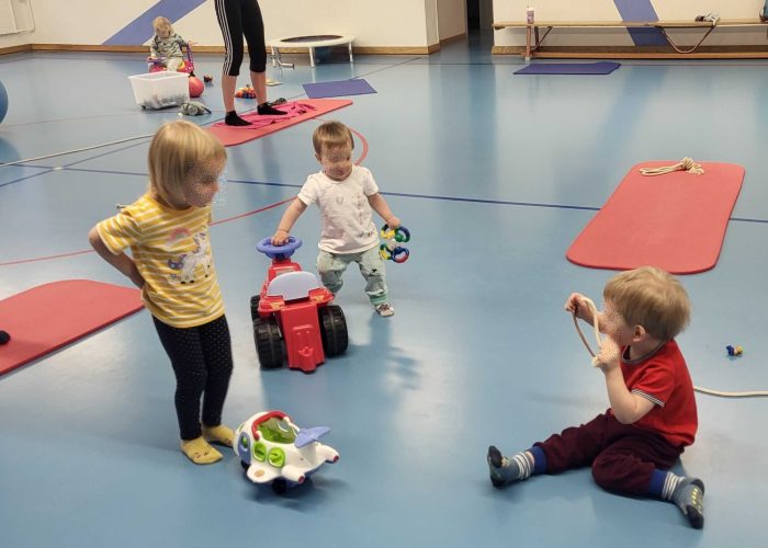 Gruppe von Müttern beim gemeinsamen Training mit ihren Babys auf Yogamatten.
